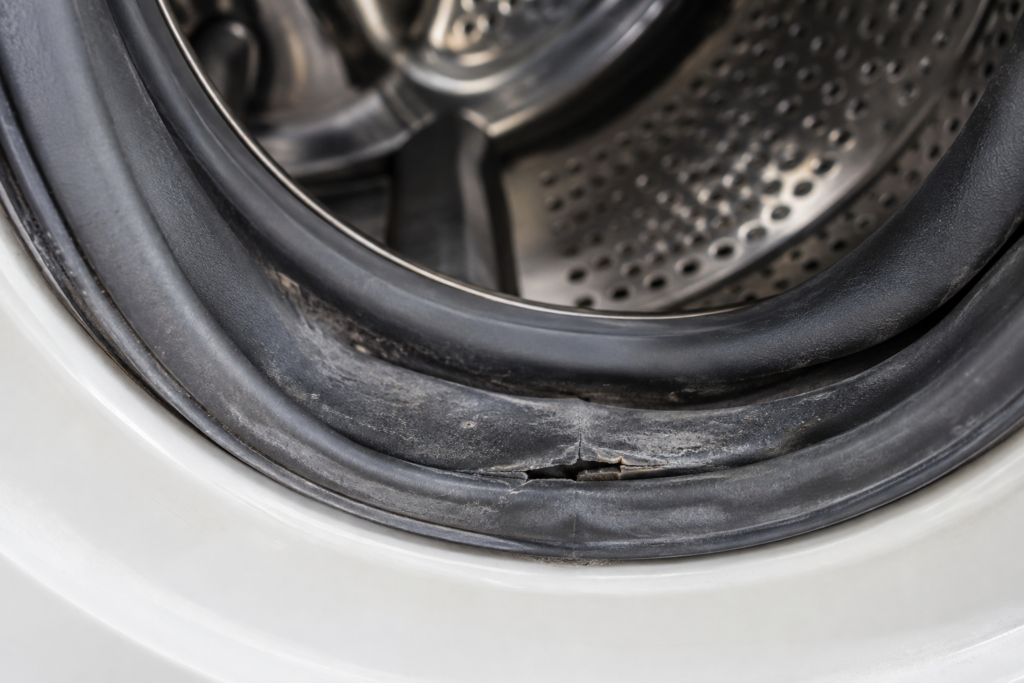 Close-up of a front-load washer's rubber door boot gasket, showing a crack and wear along its bottom fold.